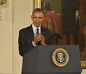 Photograph of President Obama applauding at a podium