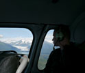 Photo of scientist Robert Spencer looking down on Mendenhall Glacier from a helicopter.