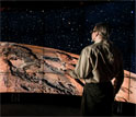 Man standing in a CAVE2 room looking at planet Mars.