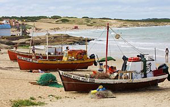 Photo of fishing boats lining the beach at Punta del Diablo, Uruguay.
