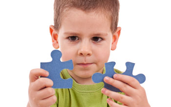 Photo of a child holding two puzzle pieces.