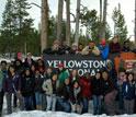Photo of people gathered around sign Yellowstone National Park with the National Park Service logo.