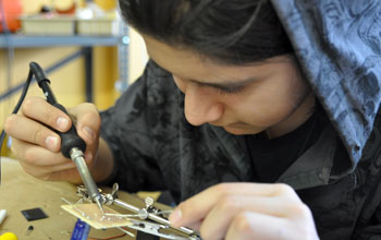 Photo of a student soldering together a solar-powered robot.